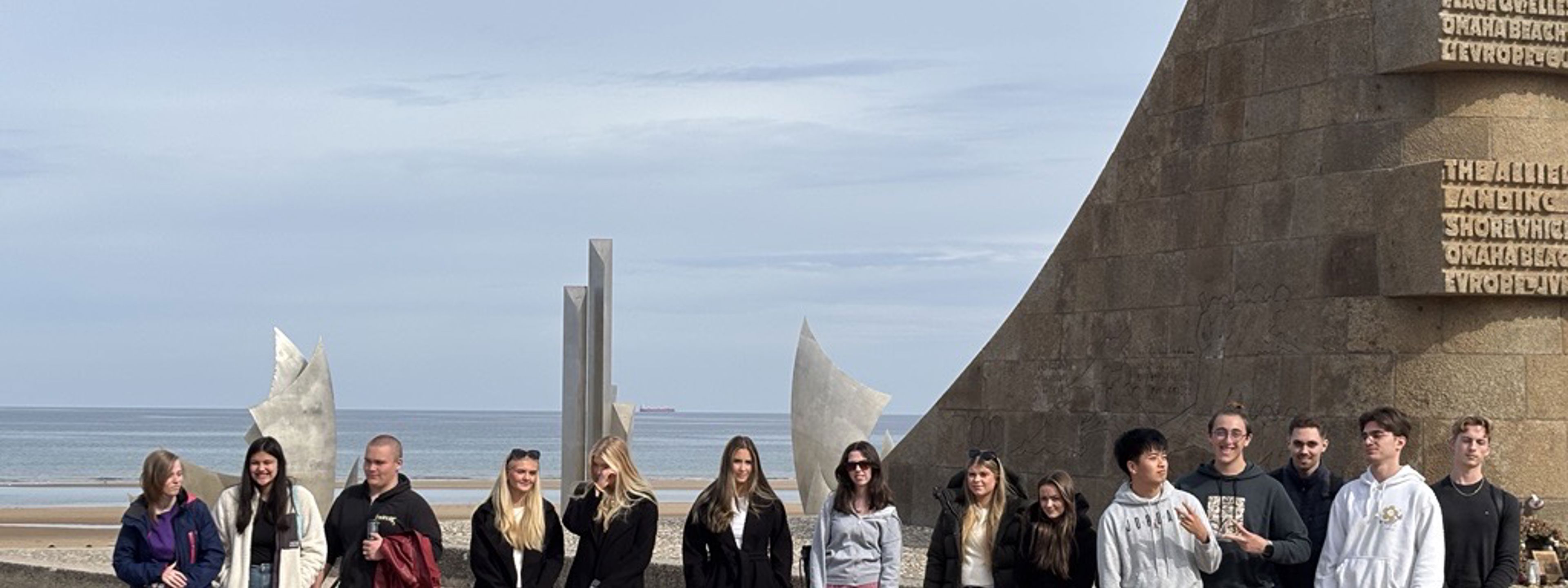 Bilete av elevar framfor minnesmerket på Omaha beach-stranda i Normandie