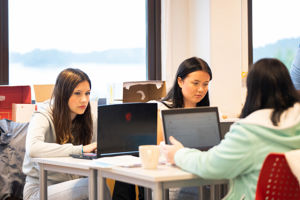Elevar som sit rundt eit bord og jobbar på pc